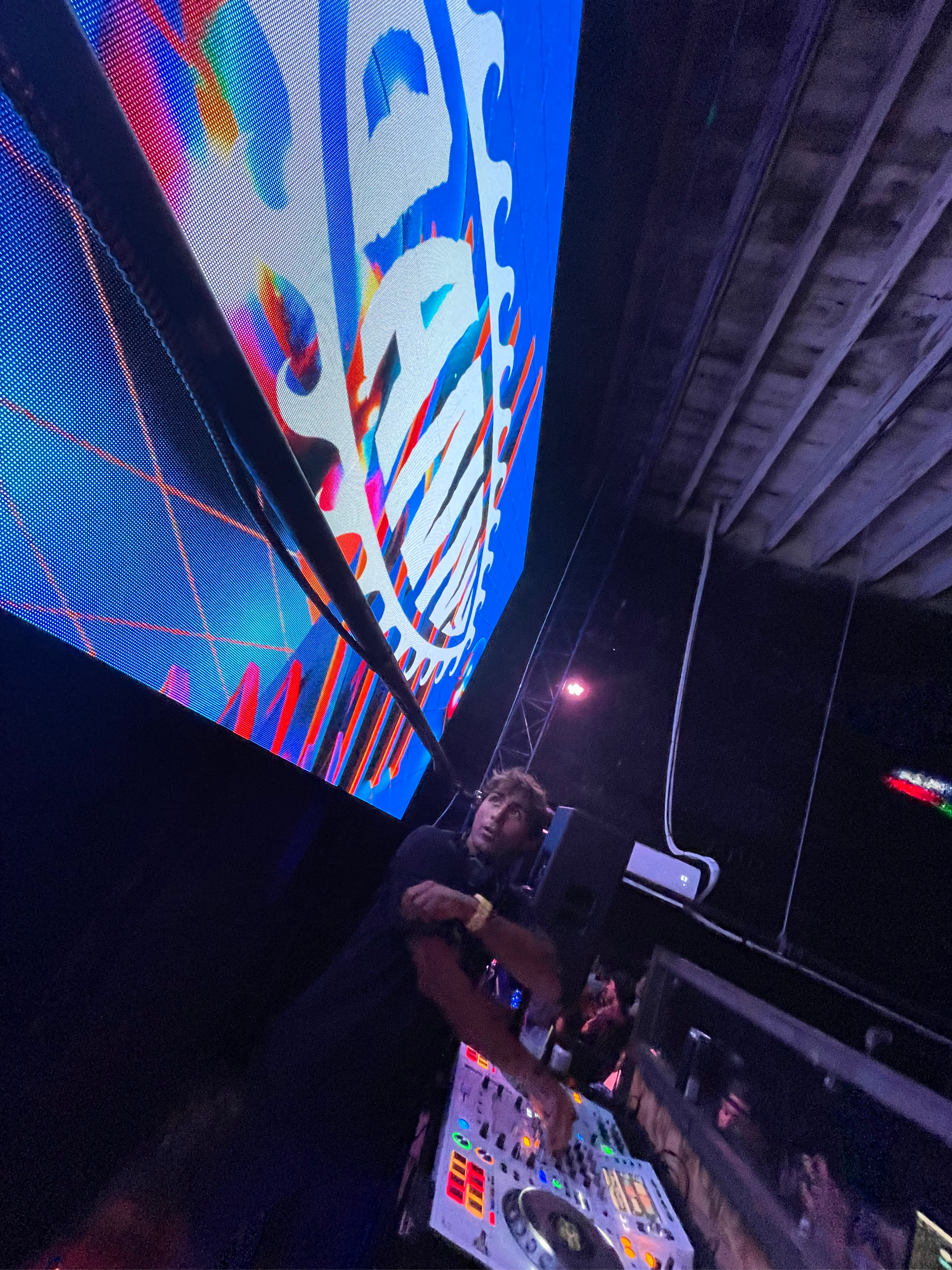 DJ Danny with DJ Danny logo behind on large screen at the club